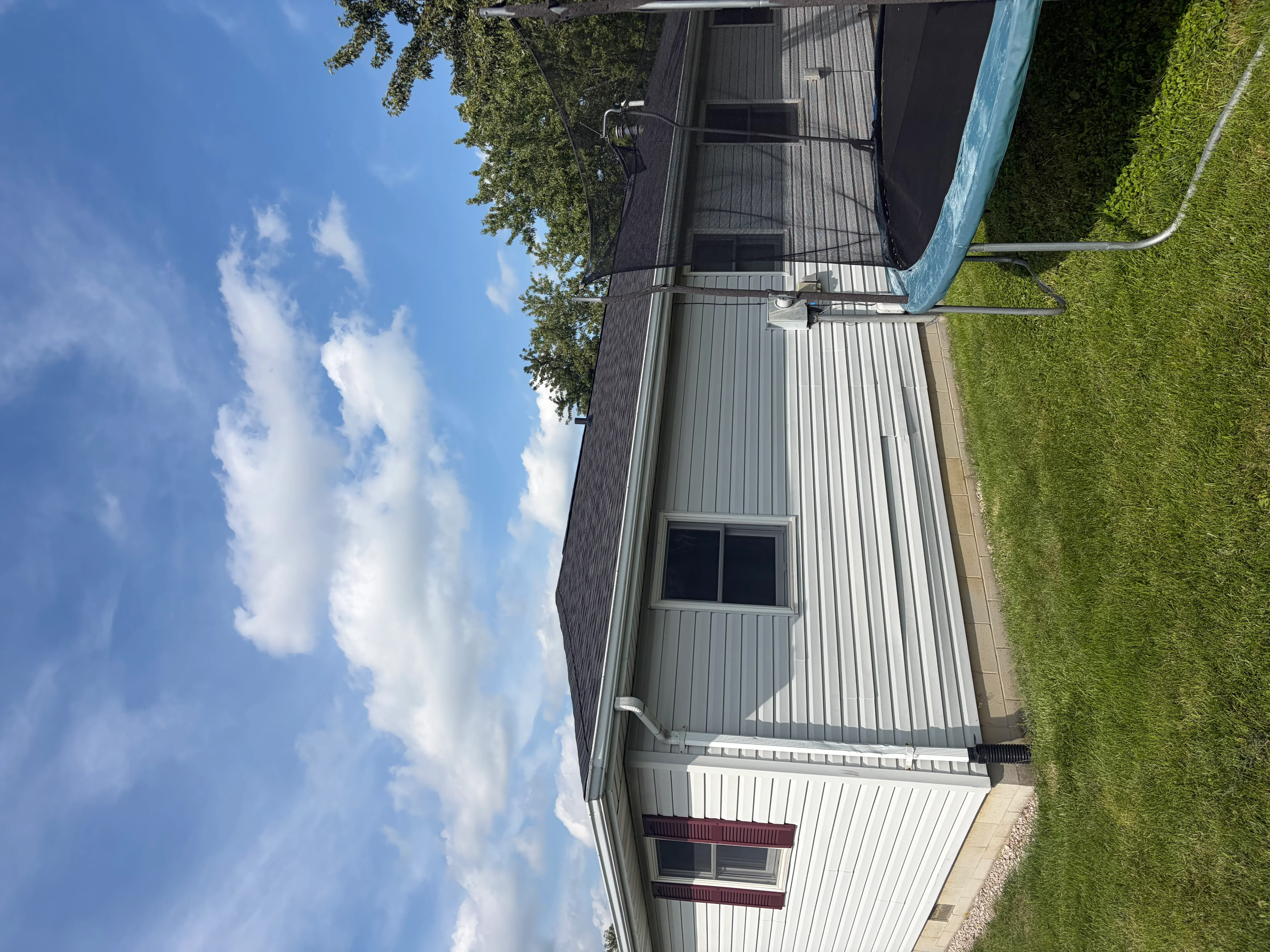 Gray and white vertical corrugated metal roof with integrated gutters and downspouts on residential structure