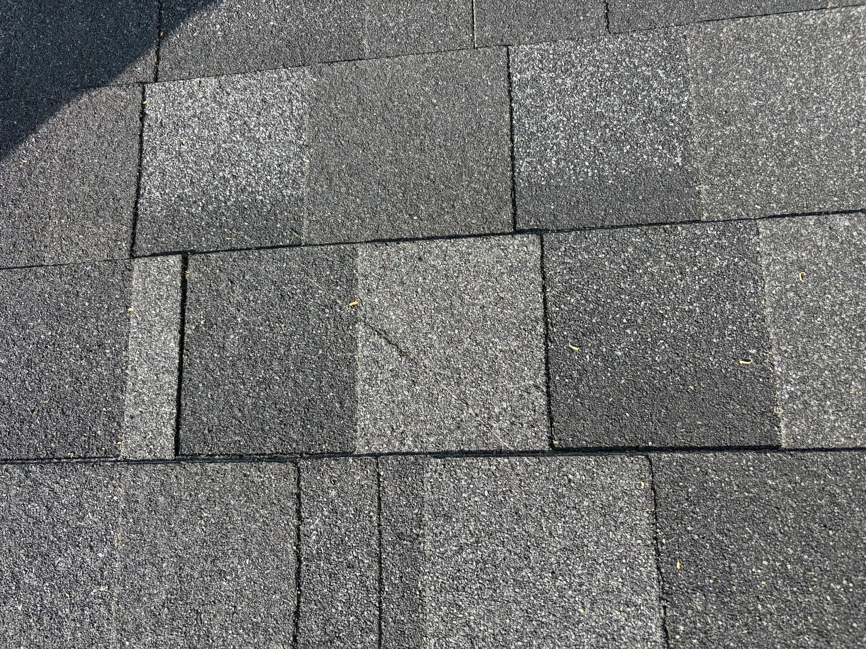 Newly installed charcoal gray dimensional asphalt shingles with offset pattern and clean seams