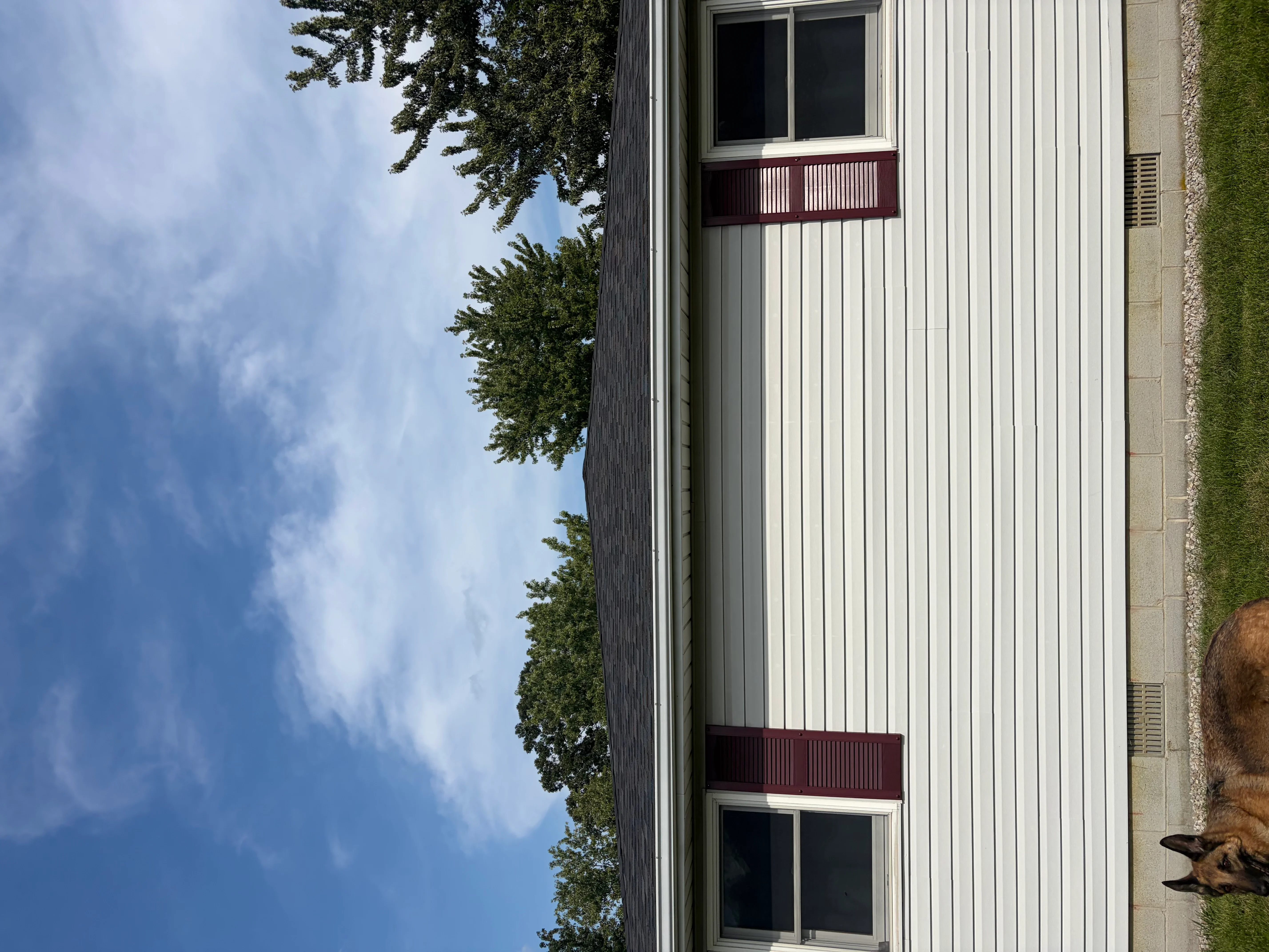 White vertical corrugated metal siding with dark red metal railings and window frames