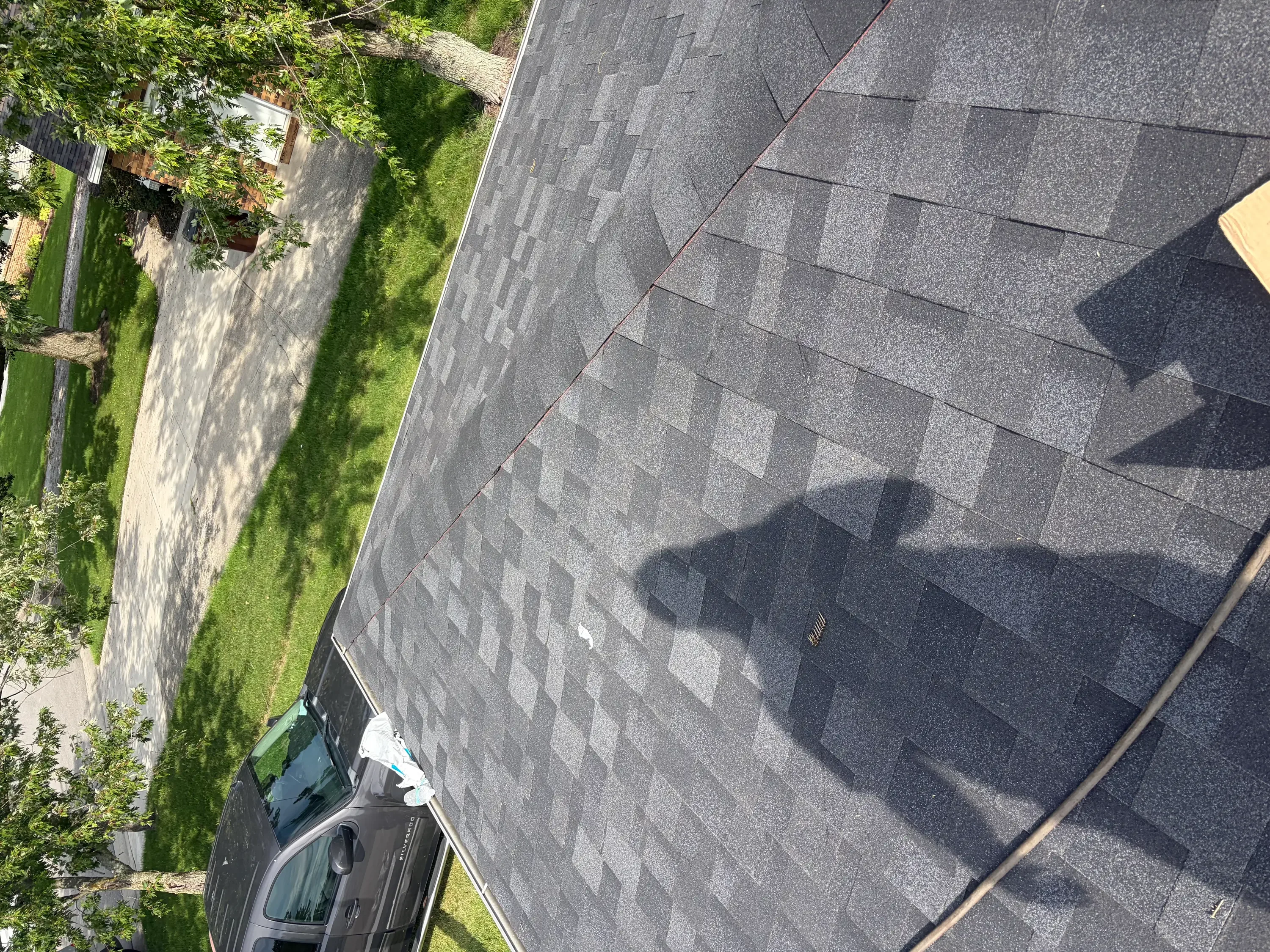 Charcoal gray architectural shingles installed on residential roof with staggered pattern and metal flashing
